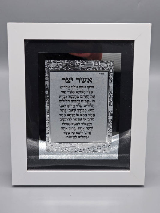 תמונת "אשר יצר" מעוצבת עם טס כסף – מסגרת לבנה